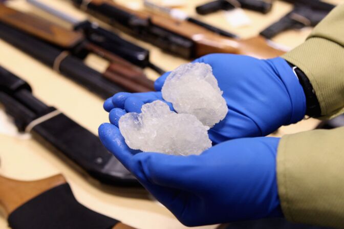 Detective Paul Baker holds two rocks of crystal meth with a street value of NZD$83,000 alongside firearms that were confiscated as part of Operation Slab at the North Shore Policing Centre on August 19, 2010 in Auckland, New Zealand.