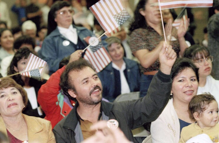People stand in a crowd waving small U.S. flags.
