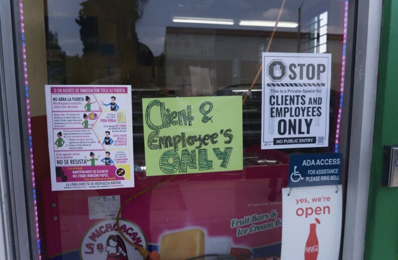 A window of La Michoacana business with multiple signs that read “CLIENT & EMPLOYEE’S ONLY” and a flyer of a know your rights guide if an immigration agent approaches to you.