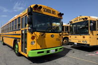 A yellow bus with a green fender. Black letters above the windshield read "SCHOOL BUS." 
