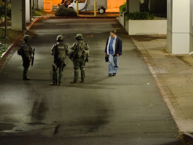 James O'Dell, staff at Cal State Fullerton walks past SWAT after being released from the Pollak Library at Cal State Fullerton in Fullerton, Calif., Wednesday, Dec. 12, 2012. Police began their campus-wide search after one of five robbery suspects, believed to be armed, allegedly barricaded himself inside a building on campus.
