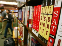 In this image there's a bookshelf in a bookstore. The shelf is lined with SAT preparation books.