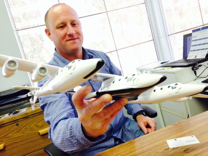 Accredited Space Agent Jay Johnson holding a model of the ship Virgin Galactic will use to take tourists into space.
