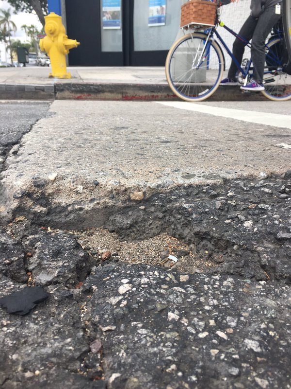 A large pothole mars a portion of Fairfax Avenue. Bike Commuter Sean Meredith shot this photo of KPCC reporter Sharon McNary during their ride on the bumpy street.
