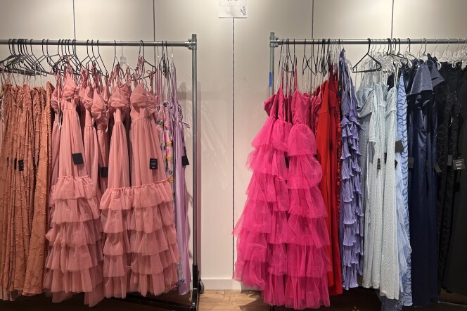 Two metal clothing racks with several different colorful dresses hanging off the top.