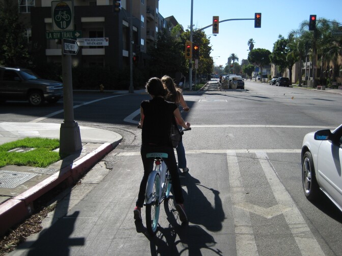 Two women ride in a bike lane.