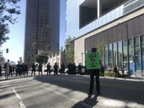 A man holding a sign that says "I am the Earth I want to live" stands in front of a line of police officers in riot gear. 