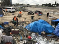 Orange County workers help a homeless woman dismantle her camp off Chapman Avenue along the Santa Ana River. The county plans to remove some 250 people living along the river to clear the space to store riprap and sand. 