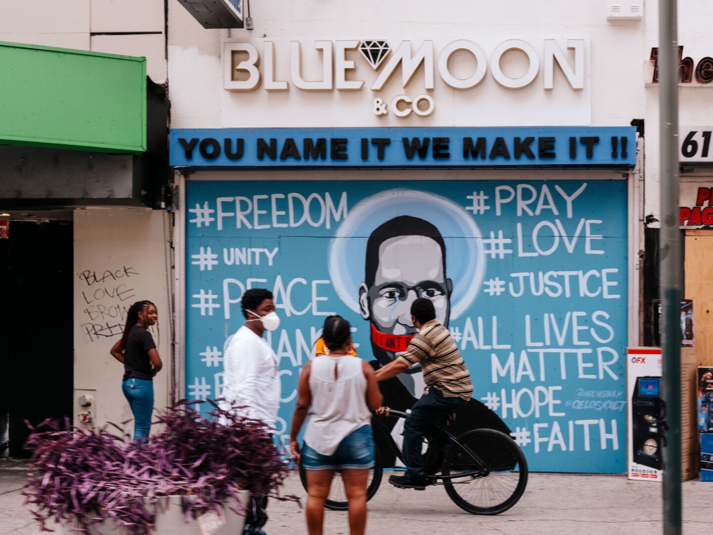 People stop to look at a George Floyd Memorial Mural painted on a boarded up business in downtown Los Angeles.