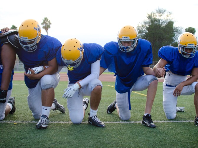 Members of La Mirada High School's Matadores football team hold hands on the field in a moment of meditation after practice in La Mirada, Wednesday, September 5, 2012.
