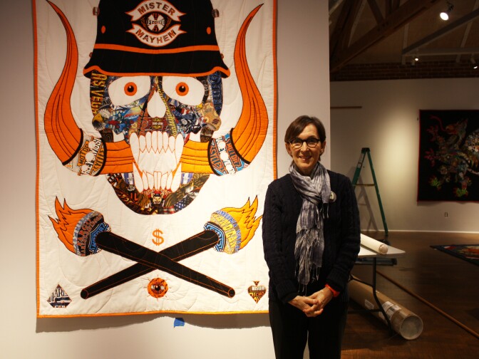 Executive Director Suzanne Isken of the Craft & Folk Art Museum stands in front of a quilt featured in her new exhibition "Man-Made: Contemporary Male Quilters."