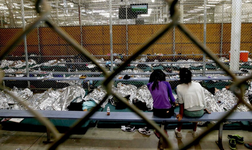 NOGALES, AZ - JUNE 18:  Two young girls watch a World Cup soccer match on a television from their holding area where hundreds of mostly Central American immigrant children are being processed and held at the U.S. Customs and Border Protection Nogales Placement Center on June 18, 2014, in Nogales, Arizona.  Brownsville, Texas, and Nogales, have been central to processing the more than 47,000 unaccompanied children who have entered the country illegally since Oct. 1. (Photo by Ross D. Franklin-Pool/Getty Images)
