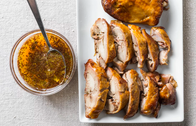 a bowl of sauce next to a plate of cooked turkey thigh