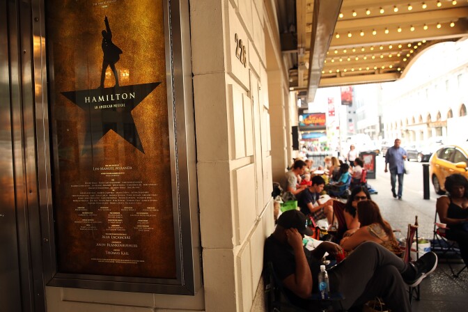 NEW YORK, NY - JUNE 21:  People, many who have been there for days, wait in line with dozens of others for tickets for the popular Broadway show Hamilton on June 21, 2016 in New York City. The Tony Award-winning Broadway hit has drawn huge crowds to the Richard Rogers theater in the hopes of getting increasingly scarce and expensive tickets. Carrying bed rolls, pillows and take-out food containers, many fans of the musical wait days in the heat and rain for a chance to get a cancellation ticket which are offered to the public once they're declined by members of the cast and crew.  (Photo by Spencer Platt/Getty Images)