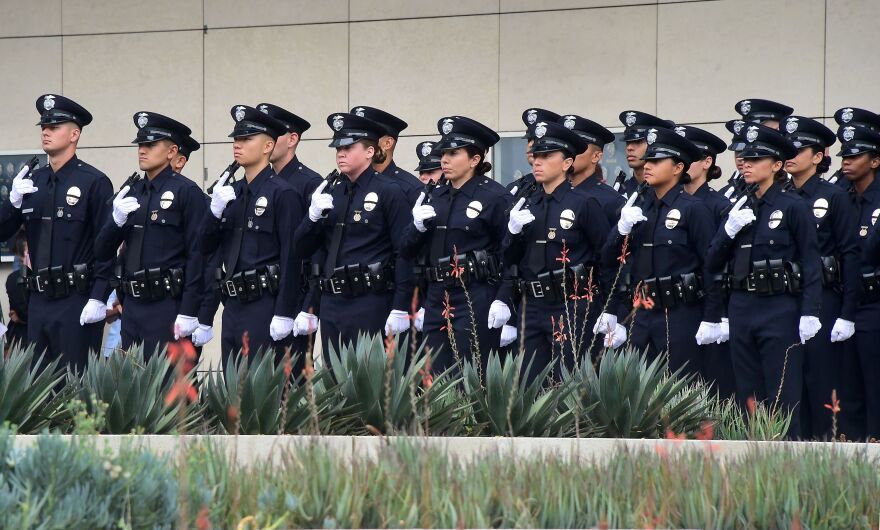 With black ribbons across their badge and holding a gun, police recruits attend their graduation ceremony at LAPD Headquarters where rappers Snoop Dogg and The Game led a peaceful demonstration outside on July 8, 2016 in Los Angeles, California, in what they called an effort to promote unity in the aftermath of the deadly shootings of police officers in Dallas.
 / AFP / Frederic J. BROWN        (Photo credit should read FREDERIC J. BROWN/AFP/Getty Images)