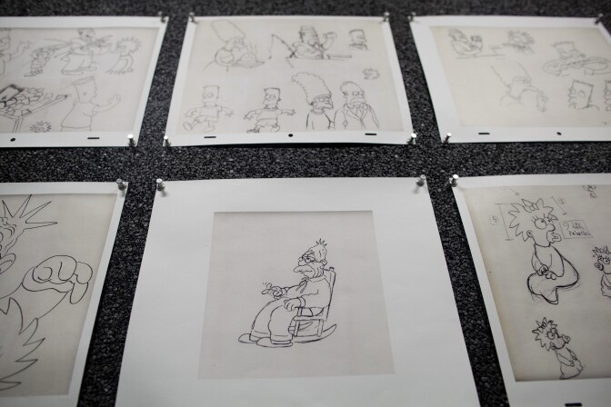 Sketches on the walls of a conference room depict different characters in "The Simpsons."