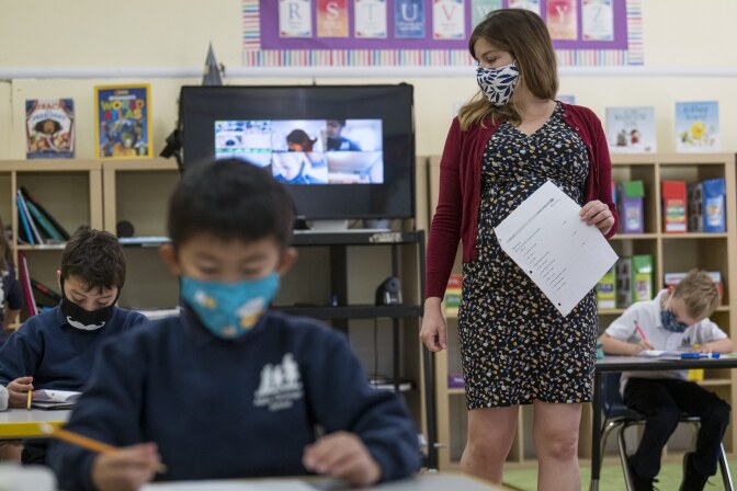 A teacher wearing a protective mask walks around the classroom during a lesson at an elementary school in San Francisco in October 2020.