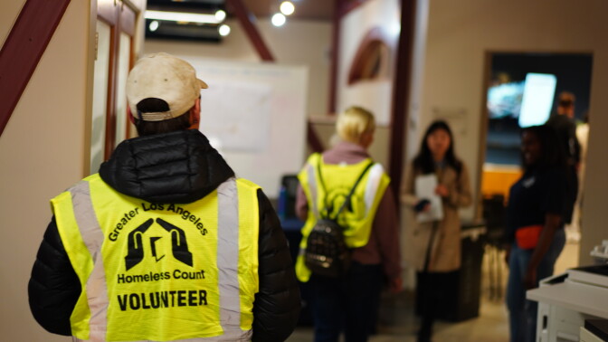 Two people wearing reflective vests walk through a hallway.