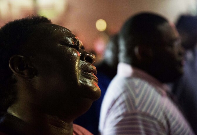 Lisa Doctor joins a prayer circle early Thursday, June 18, 2015, down the street from Emanuel AME Church following a shooting Wednesday night in Charleston, S.C. A white man opened fire during a prayer meeting inside the historic black church, killing multiple people, including the pastor, in an assault that authorities described as a hate crime. (AP Photo/David Goldman)