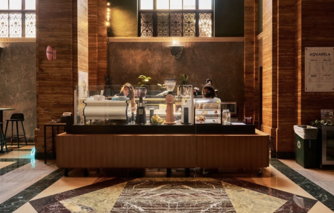 A coffee stand in the middle of a gorgeous art deco building, with an inlaid marble floor and wood panelling