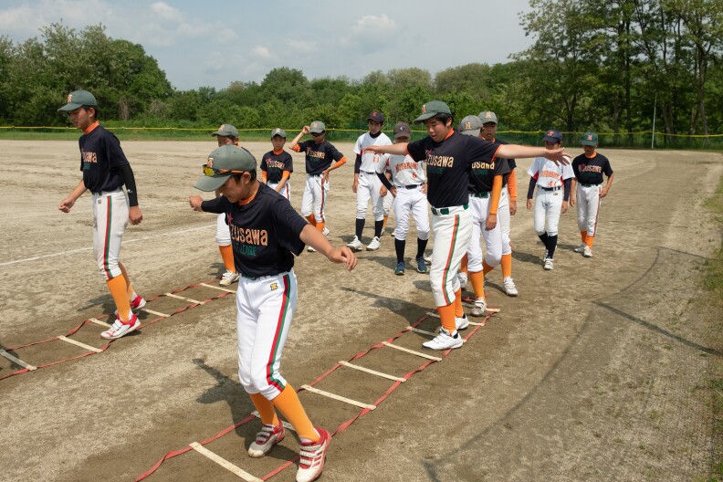 週末の練習中、アジリティトレーニングのため梯子に登る水沢パイレーツの選手たち。 日本の少年野球選手は、バントやダブルプレーなどのスキルを身につけるために反復練習を行っています。