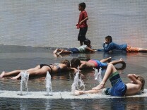 Children try to cool down and take advantage of the Grand Park fountain in downtown Los Angeles on Wednesday, July 5, 2017. Forecasters say a new heat wave is setting in across the interior of Southern California, and the southern Sierra Nevada is facing a period of elevated fire danger. The National Weather Service says the heat is coming from high pressure building over the desert Southwest that will expand westward. (AP Photo/Richard Vogel)