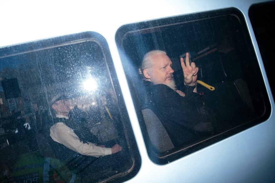 Julian Assange gestures to the media from a police vehicle on his arrival at Westminster Magistrates court on April 11, 2019 in London, England.