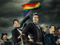 Five people on a boat flying the Pride flag
