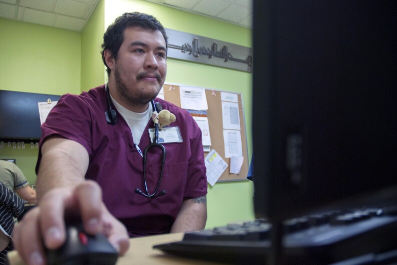 Alex Figueroa, a medical assistant at the UMMA Clinic in South Los Angeles, checks on a patient's progress on March 12. This clinic and others like it are relying more on the skills of its nursing staff as the growing number of patients strains the ratio between caregivers and those in need of medical attention.