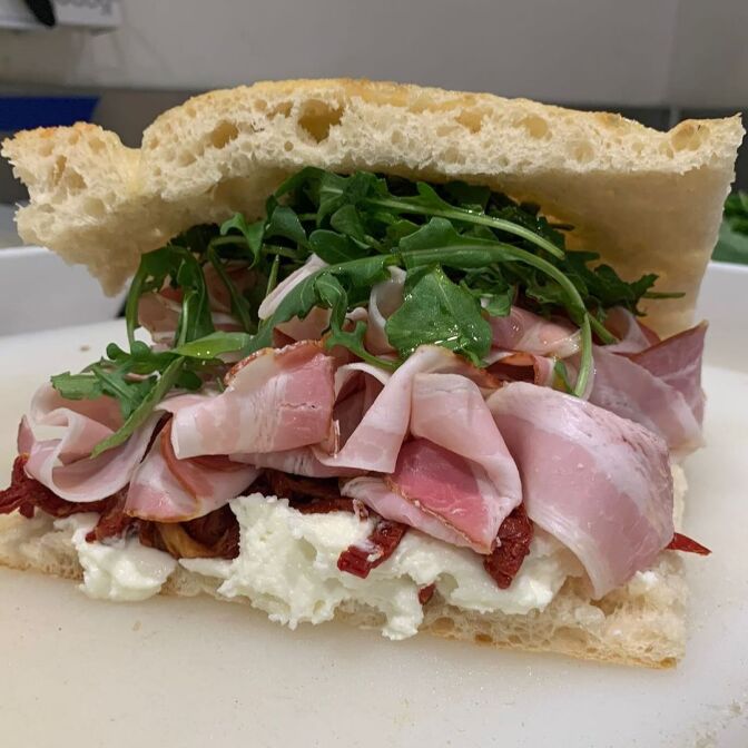 A pancetta, pecorino cream, sun dried tomato, and arugula sandwich. 