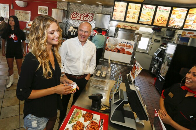 File: Sports Illustrated swimsuit model Hannah Ferguson, left, orders lunch alongside CKE Restaurants CEO Andy Puzder after a news conference on Wednesday, Aug. 6, 2014 in Austin, Texas declaring Carl's Jr.'s commitment to the state of Texas.