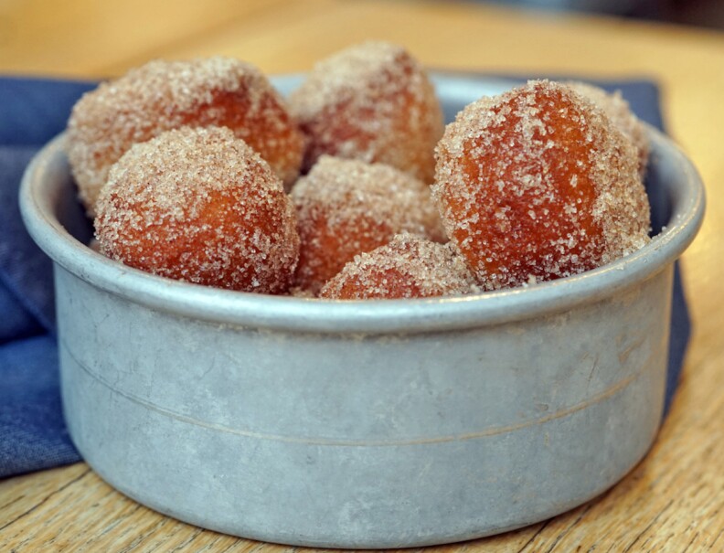 a small ceramic bowl holds several donut holes dusted with sugar