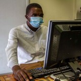 HARARE, ZIMBABWE - JANUARY 05: A man is seen working wearing a mask in his office during the lockdown on January 5, 2021 in Harare, Zimbabwe. Following crowded new year's eve celebrations where coronavirus sanitary protocols were scarce, the Zimbabwe's capital has entered a strict 30-day lockdown. As of 3rd January, Zimbabwe recorded 15,265 Covid-19 infection cases and 380 deaths. (Photo by Tafadzwa Ufumeli/Getty Images)