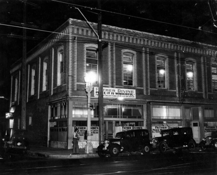 A corner brick building is lighted at night