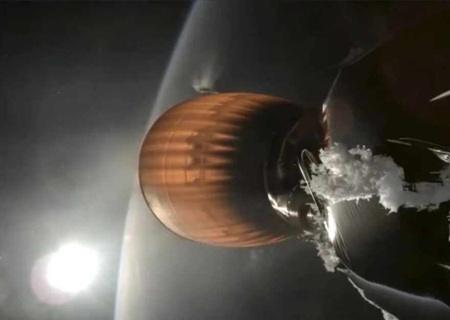 The sun is on the bottom left corner, while a flaming rocket booster is shown in the middle of the screen floating over earth