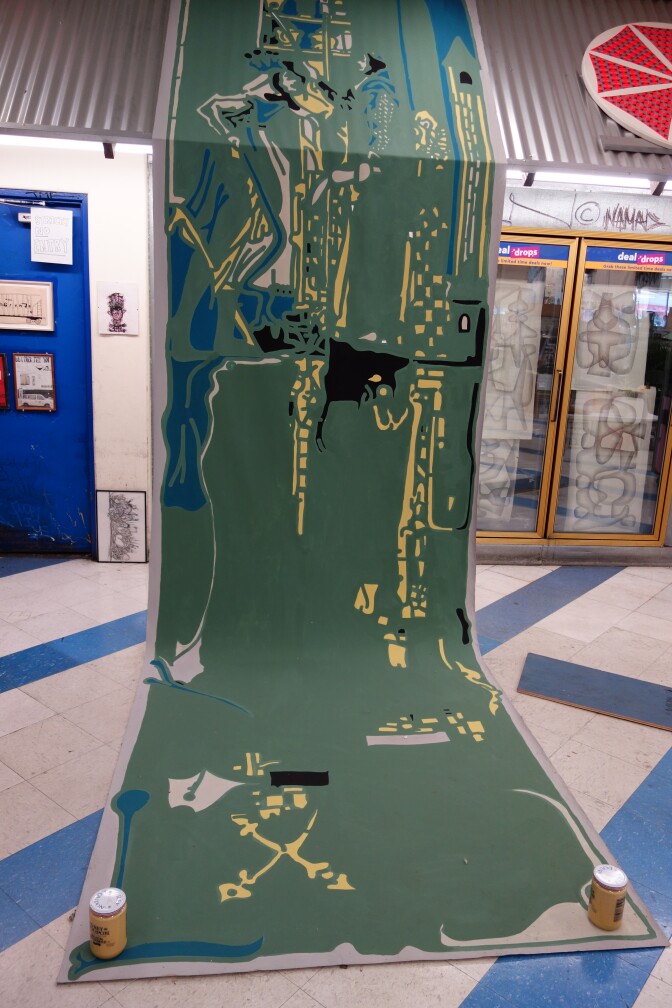 A large artwork held down by two mustard bottles.