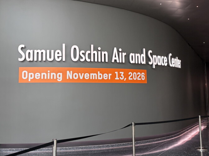A wall sign reads 'Samuel Oschin Air and Space Center, Opening November 13, 2026' behind a stanchion barrier.