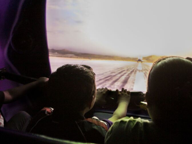 Children hang on to the safety rails inside the Pulseworks simulator ride during a preview of Endeavour: The California Story exhibition at the California Science Center.