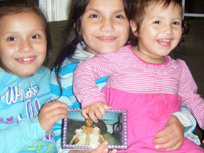 Twins Fabiola (left) and Fatima Mann Perez, 7, sit with sister Cassandra, 1, and hold a photo of their father Jorge Perez. He was barred from the U.S. for at least 10 years, until 2017, after he and his U.S. citizen wife, Anita Mann Perez of Graham, North Carolina, applied for Jorge?s legal residency. 