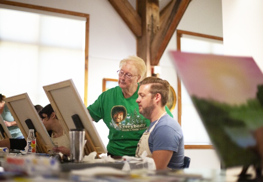Sandra Hill offers guidance to Mark Scheiffley during a Bob Ross painting class at the Franklin Parks Art Center in Purcellville, Va., on Sept. 20. Hill is one of more than 3,000 people certified to teach the Bob Ross wet-on-wet painting technique.
