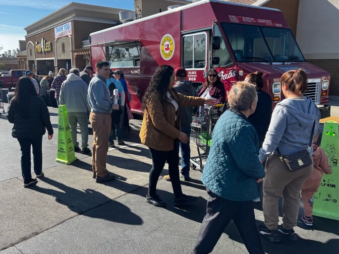 A group of people stand in a parking next to a red food truck