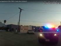 A police car is visible with lights flashing at dusk in a wide angle shot marked as body worn camera 2