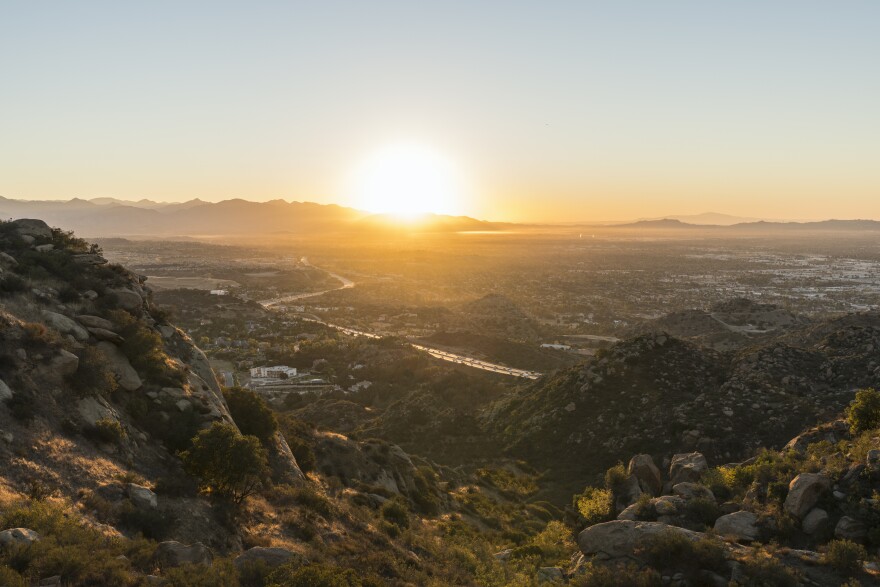 A view of the sunrise over mountains and a freeway pass behind the mountains.