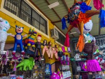 A party store from the outside, full of colorful piñatas hanging from the ceiling. 