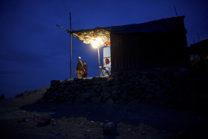 Afghans look on from a lit hut at dusk in Kabul on April 18, 2012. Poverty and an ongoing insurgency by the ousted Taliban still pose a threat to the stability of the country. AFP PHOTO/ JOHANNES EISELE (Photo credit should read JOHANNES EISELE/AFP/Getty Images)