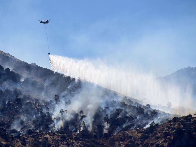 A helicopter drops water over a hillside at Lake Isabella, California on June 24, 2016.