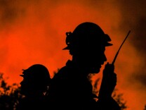 Firefighters watch the Blue Cut wildfire burning near Cajon Pass, north of San Bernardino, California on August 16, 2016. 
A rapidly spreading fire raging east of Los Angeles forced the evacuation of more than 82,000 people on August 16 as the governor of California declared a state of emergency. Despite the efforts of 1,250 firefighters with more on the way, none of the inferno was contained as of late on August 16 , state firefighting agency Cal Fire spokeswoman Lynne Tolmachoff told AFP. The wildfire poses "imminent threat to public safety, rail traffic and structures," according to the website, which said 82,640 people fell under an evacuation warning. / AFP / RINGO CHIU        (Photo credit should read RINGO CHIU/AFP/Getty Images)
