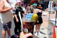 A "Chicken Charlie's" Dr. Pepper is held up in front of a crowd of OC Fair people.