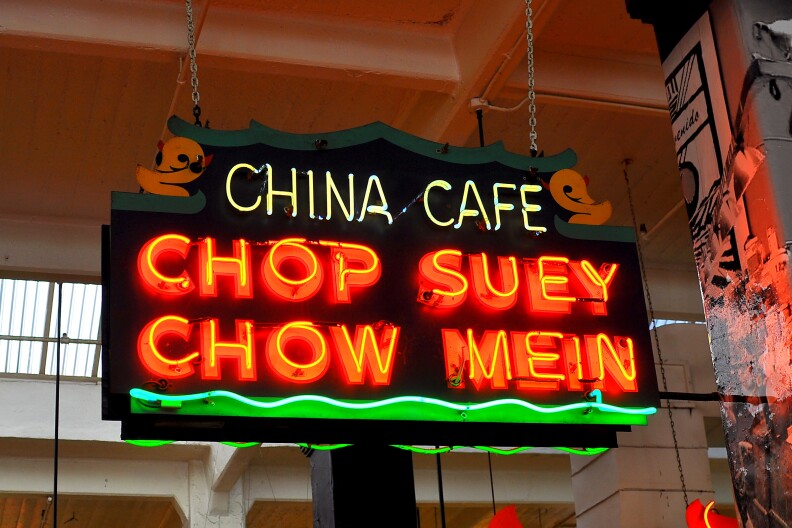 A bright neon sign says China Cafe in white and Chop Suey Chow Mein in bright orange