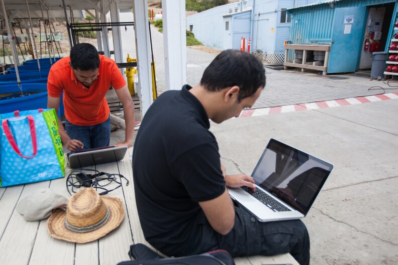 Supreeth Subbaraya (left) and Arvind Pereira conduct electronic tests over a satellite connection with a submersible robot from a dock on Catalina Island.
